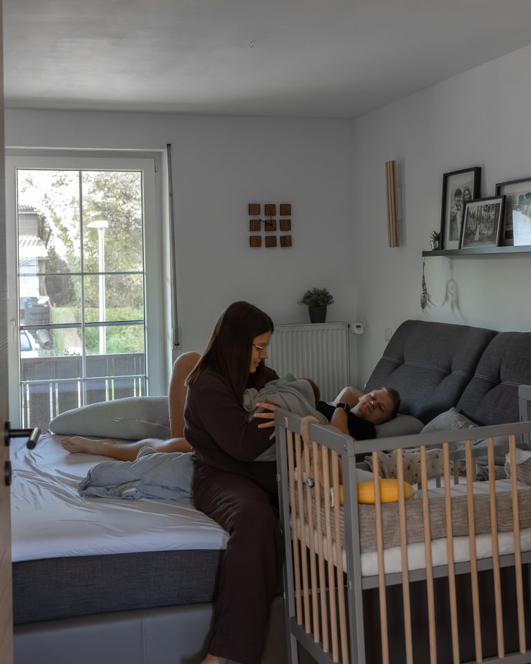 Ehepaar und Neugeborenes im Wochenbett bei dokumentarischer Familienfotografie